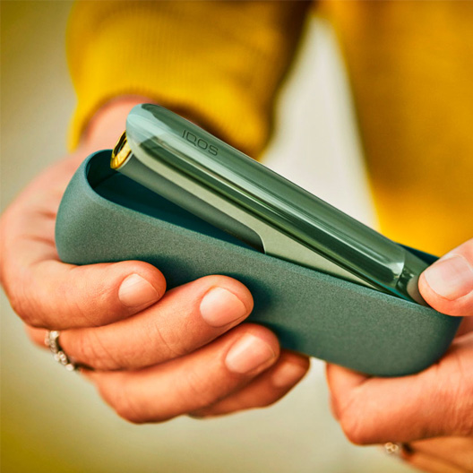 IQOS ILUMA verde abriéndose en manos de una persona