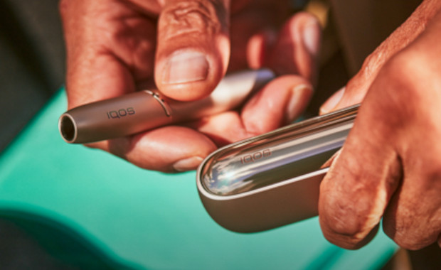 Jemand, der zeichnet, hält ein IQOS ILUMA in der Hand