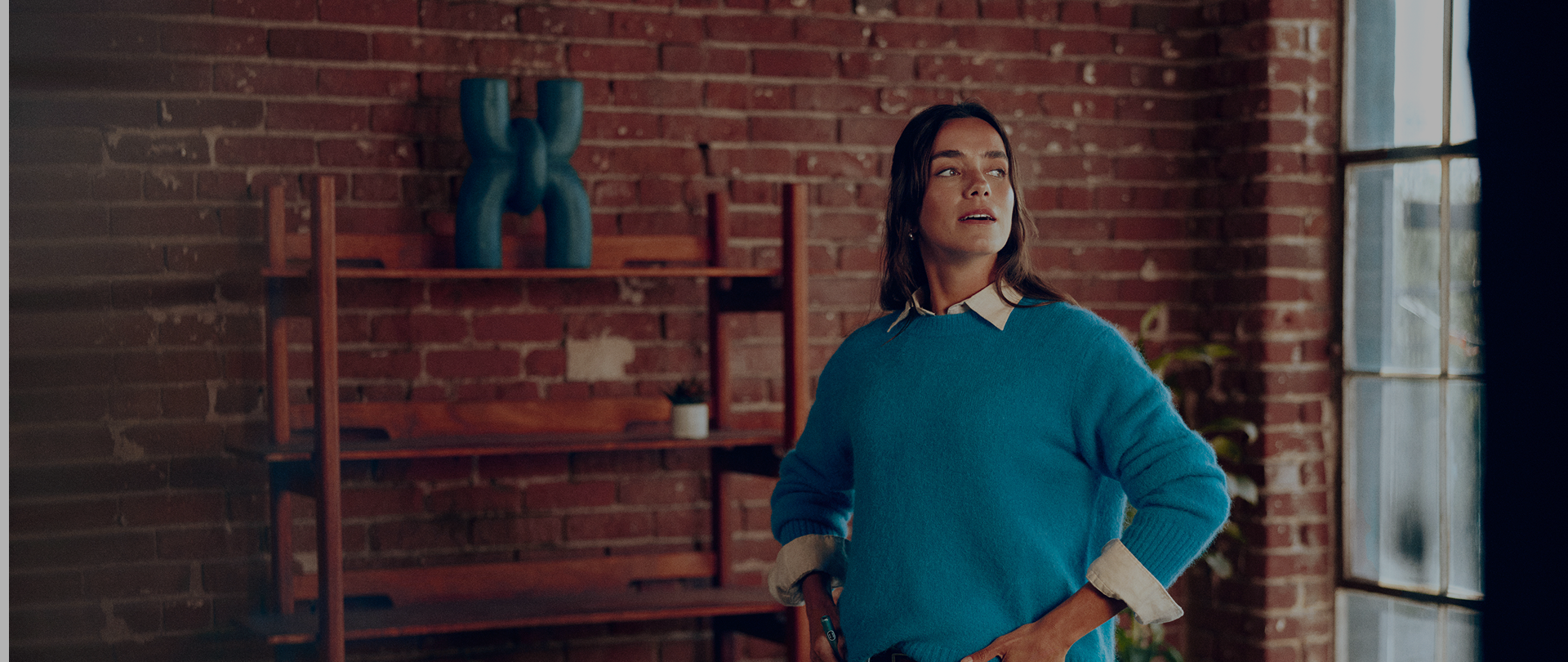 Mujer en sala de ladrillo rojo usando Iluma i con luz cálida