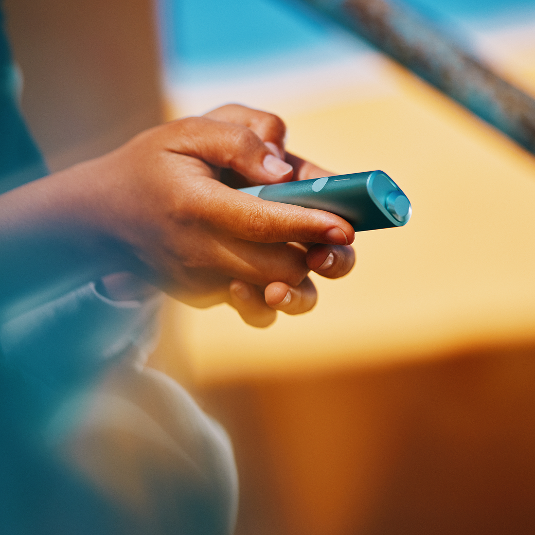 IQOS Iluma i ONE turquesa sobre mesa con boceto técnico y herramientas formato pequeño