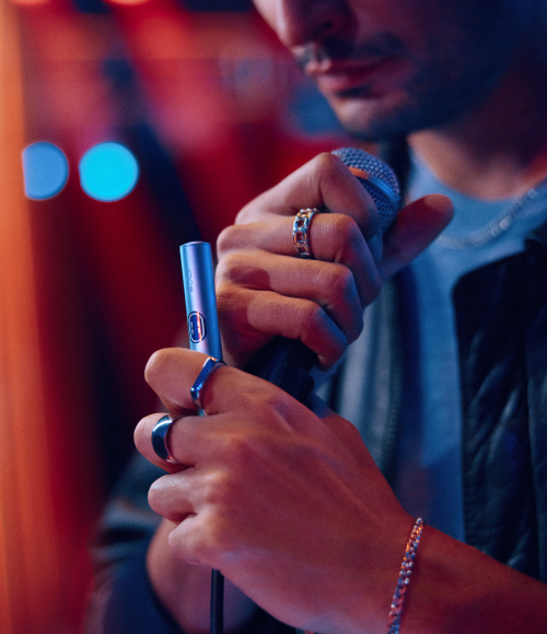 Persona usando IQOS ILUMA en un ambiente nocturno, con texto: “Sin olor a cigarro, sin ceniza”.