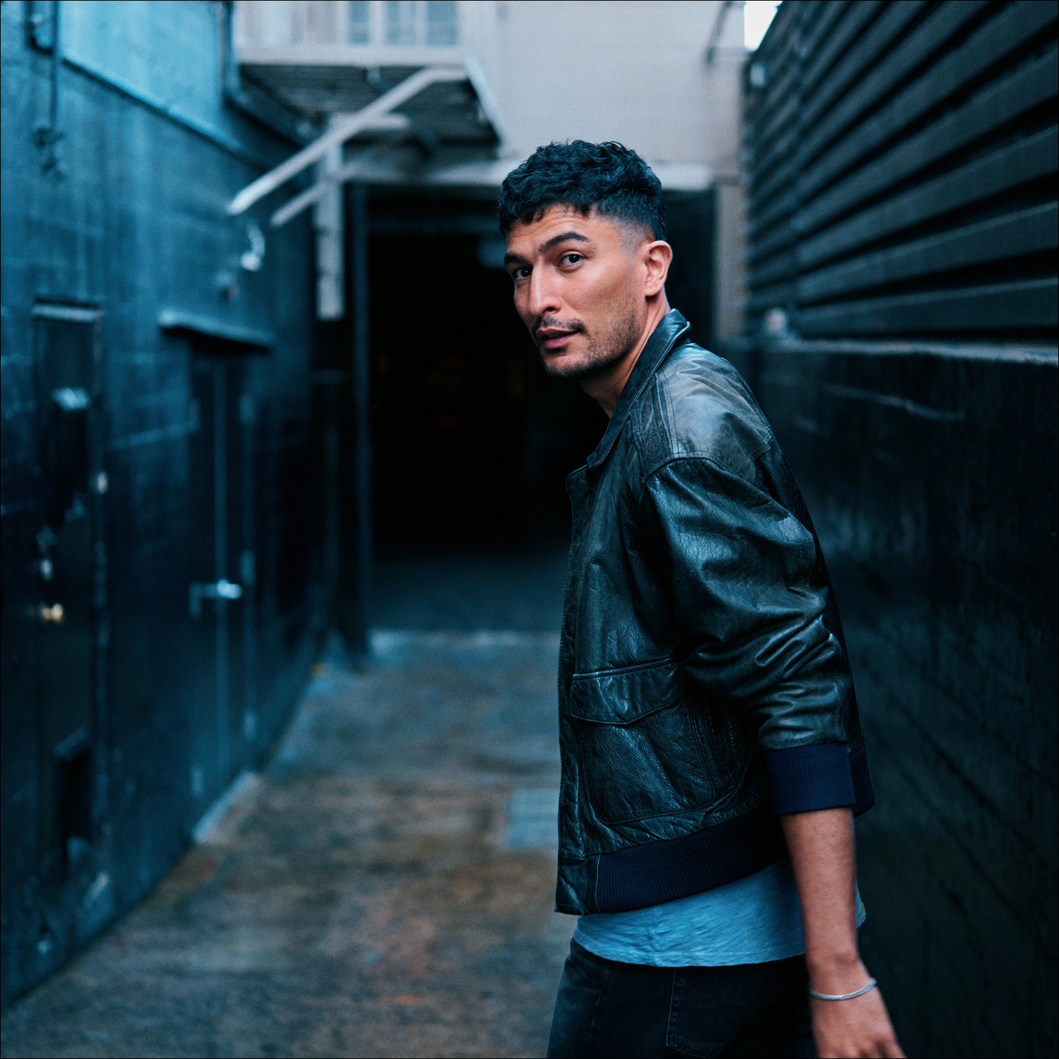 Persona posando en un pasillo oscuro sosteniendo un IQOS ILUMA i turquesa.