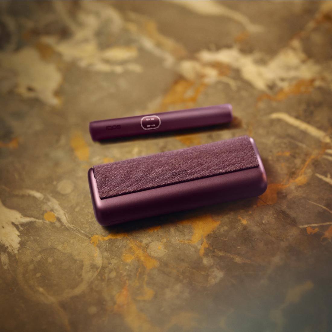 Persona sosteniendo IQOS Iluma i turquesa con luces urbanas desenfocadas