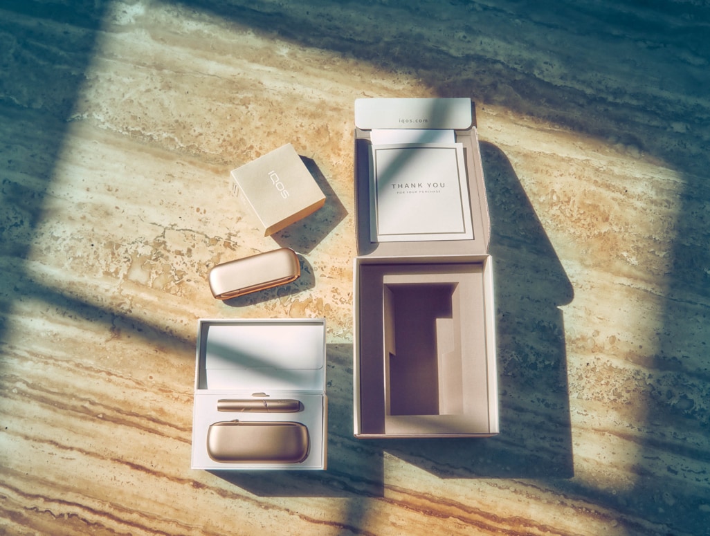 Gold IQOS Duo out of its packaging on a wooden table