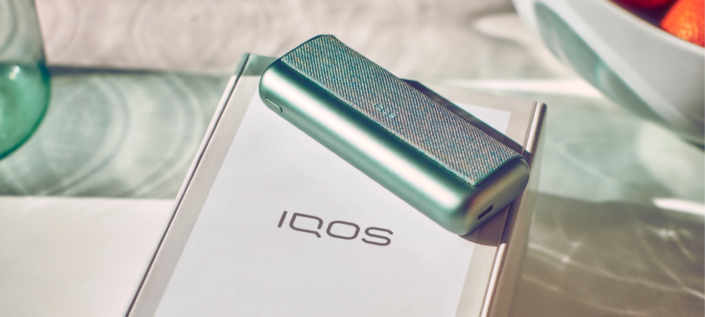 A Jade Green IQOS ILUMA PRIME Pocket Charger on an IQOS box.