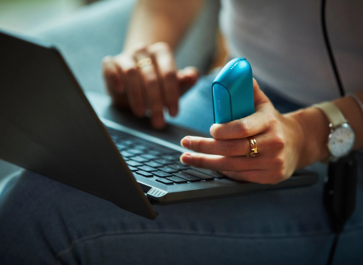 A person conducts an online diagnostic on a black IQOS ILUMA prime charger