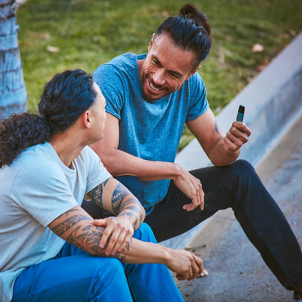 Two adults vaping outdoors