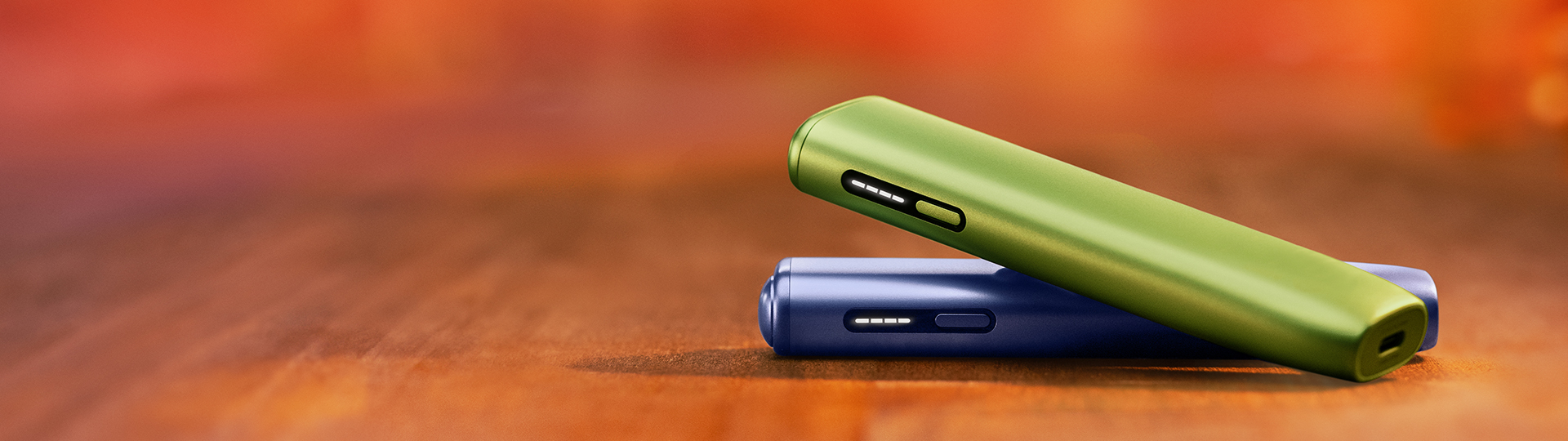 IQOS ILUMA i ONE naprava v vijoličnem ovitku nad rdečo IQOS ILUMA i ONE napravo