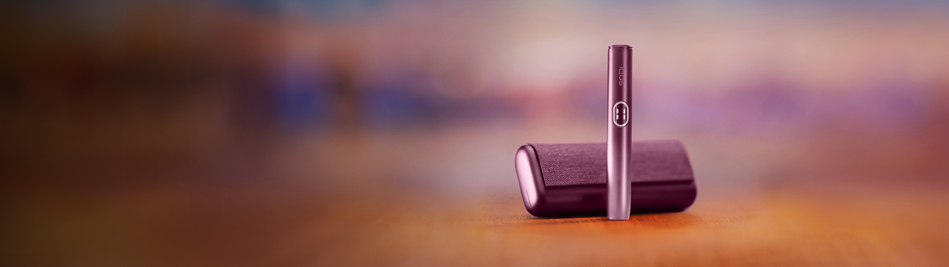 Držalo naprave IQOS ILUMA i PRIME v bordo barvi Garnet Red stoji pokončno pred žepnim polnilnikom