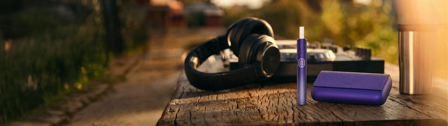 Zariadenia IQOS ILUMA i PRIME na drevenom stole.