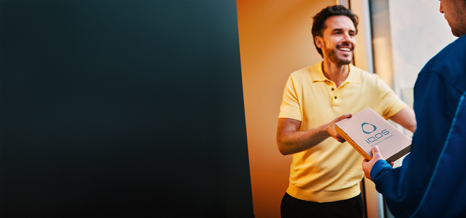 Muž drží v ruke IQOS zásielku a usmieva sa.