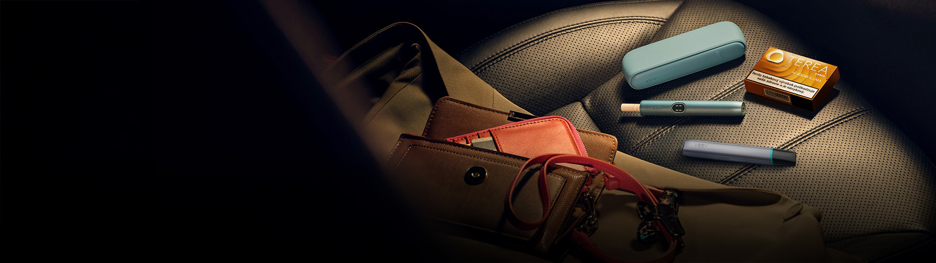 Zariadenia IQOS ILUMA i a VEEV ONE na sedadle auta.