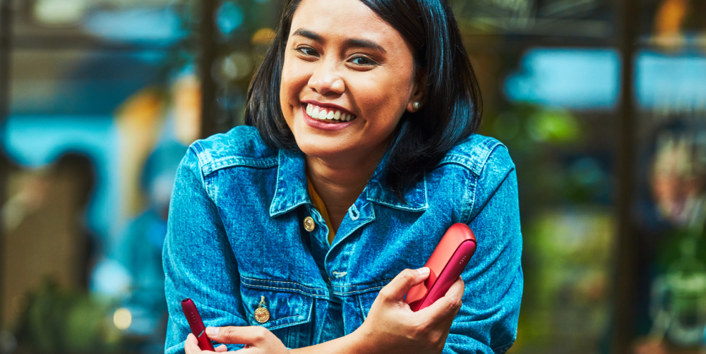 Smiling woman holds IQOS 3 device