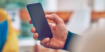 Človek držiaci mobilný telefón.