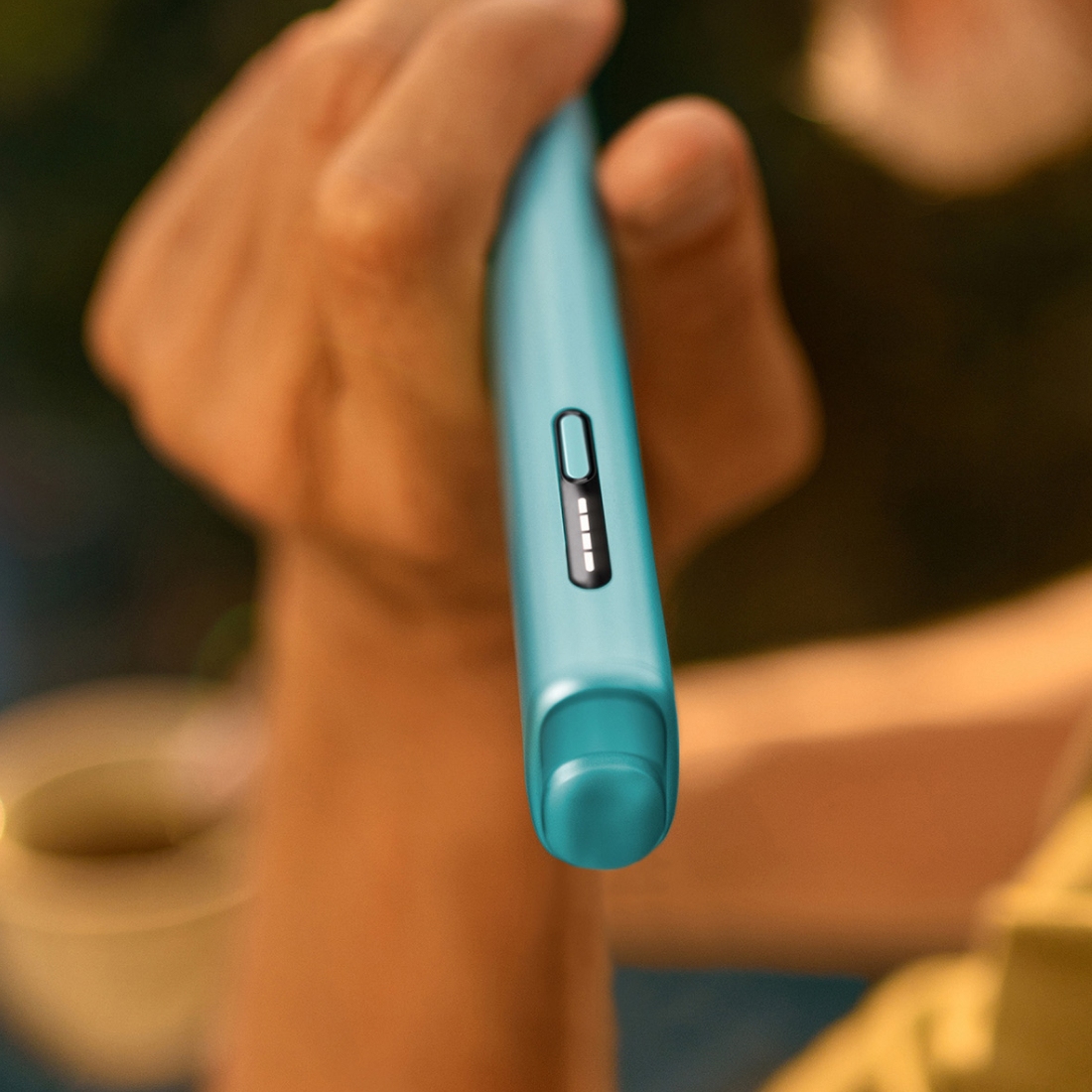 Homme tenant un appareil IQOS ILUMA i ONE, vu du côté gauche