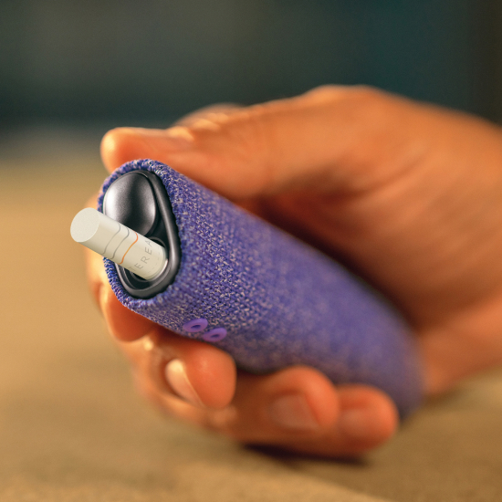Person holding IQOS ILUMA i ONE with Tobacco Stick inserted