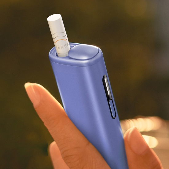 Person holding IQOS ILUMA i ONE with Tobacco Stick inserted