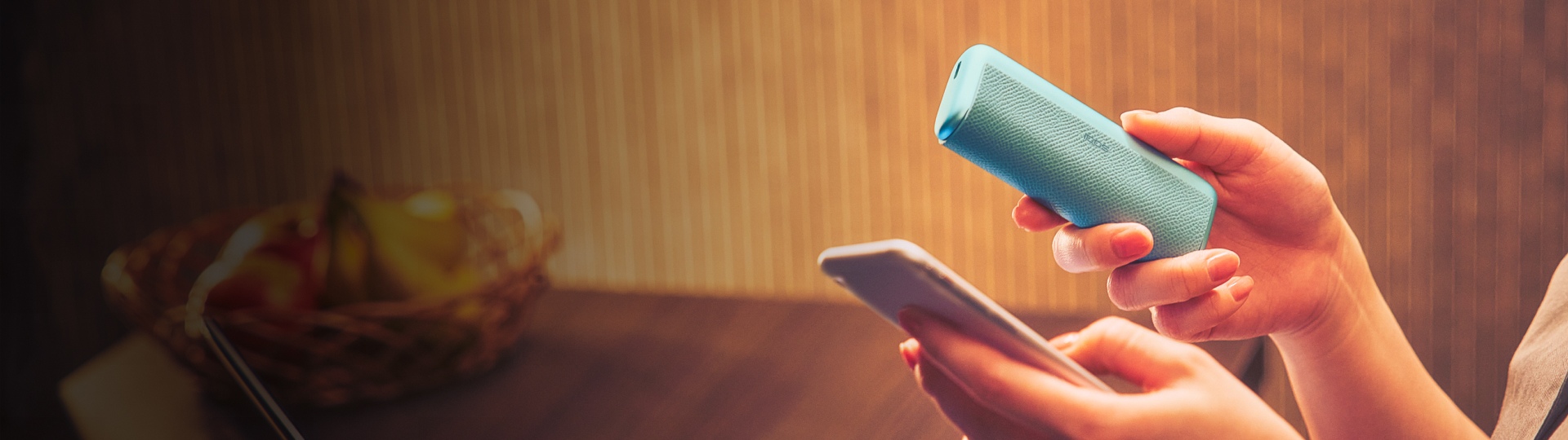 Hands holding a blue IQOS ILUMA device and a phone