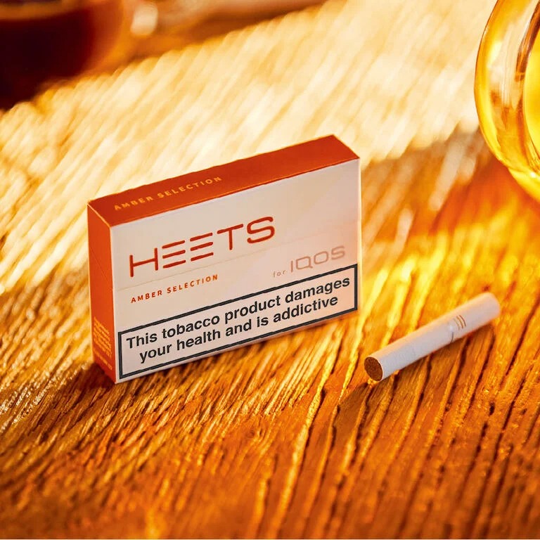 A solid woman in jacket holds IQOS