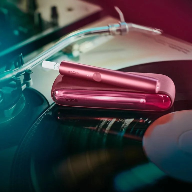 A  [colour] IQOS device with sticks inserted on a record turntable.