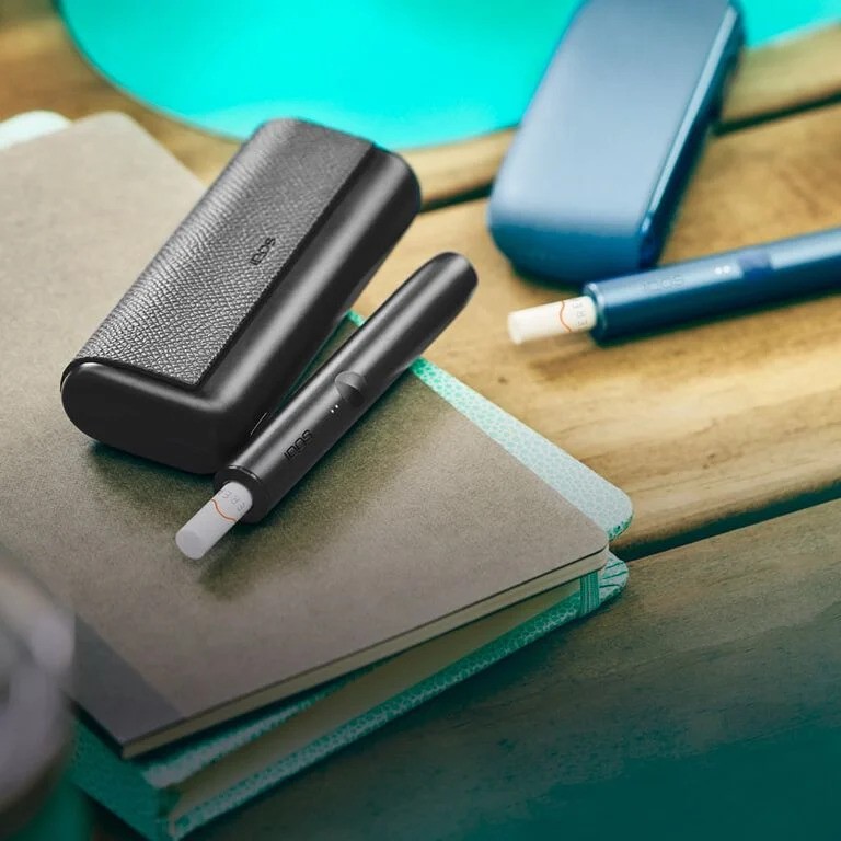 An Obsidian IQOS device and a [colour] IQOS device with sticks inserted