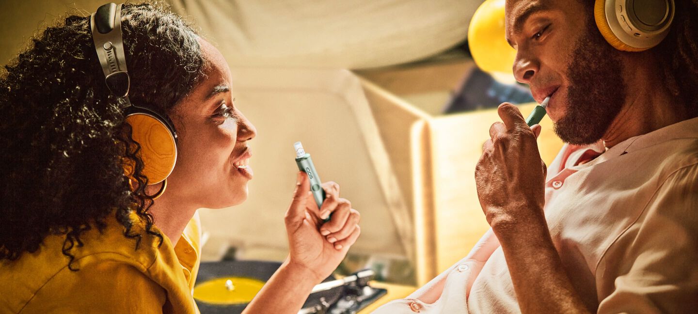 A couple listening to music while using an IQOS device.
