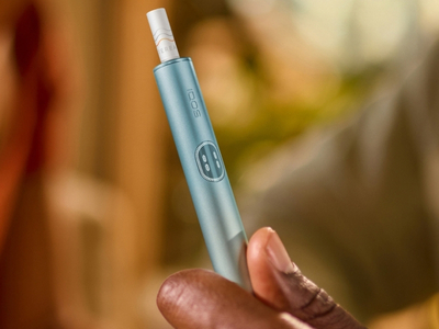 Hand holding a Breeze Blue IQOS Iluma i Holder with a blurred background