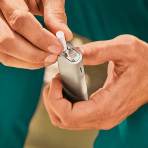 A laptop computer and IQOS device  on a table.