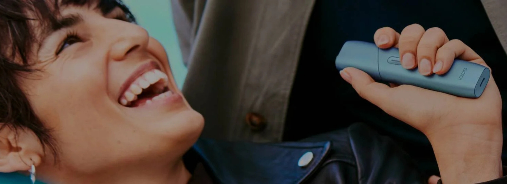 Smiling person holding IQOS Originals Duo holder in red color.