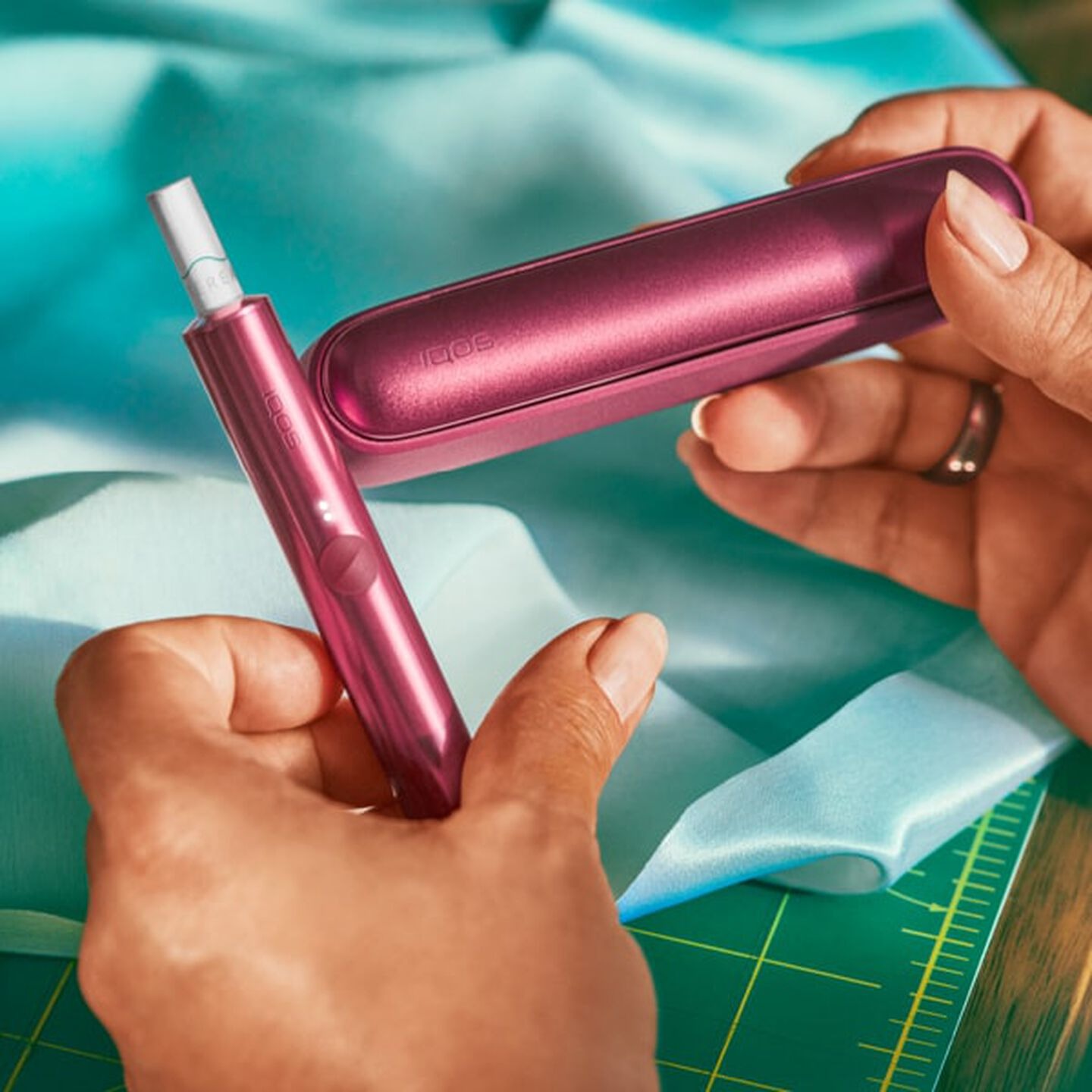 A person placing an IQOS ILUMA Pocket Charger into a charging station.