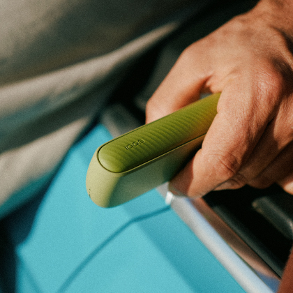 A hand holding IQOS ILUMA i device pocket charger