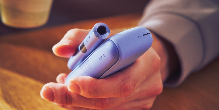 Perangkat IQOS ILUMA i sedang dipegang dan diperiksa selama troubleshooting