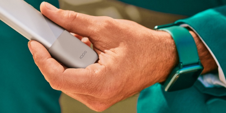 A hand holding a Pebble Beige IQOS ONE device.