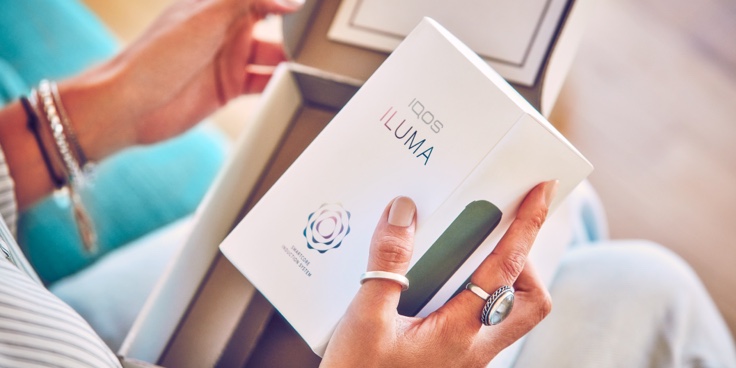 Hands unboxing an IQOS device.