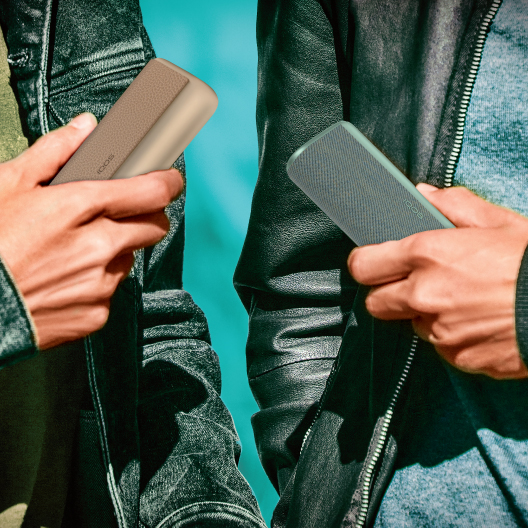 A person holding a pack of TEREA sticks while holding an IQOS ILUMA device.