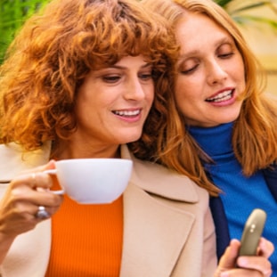 Black IQOS 3 device and mobile phone in two people's hands Black IQOS 3 device and mobile phone in two people's hands