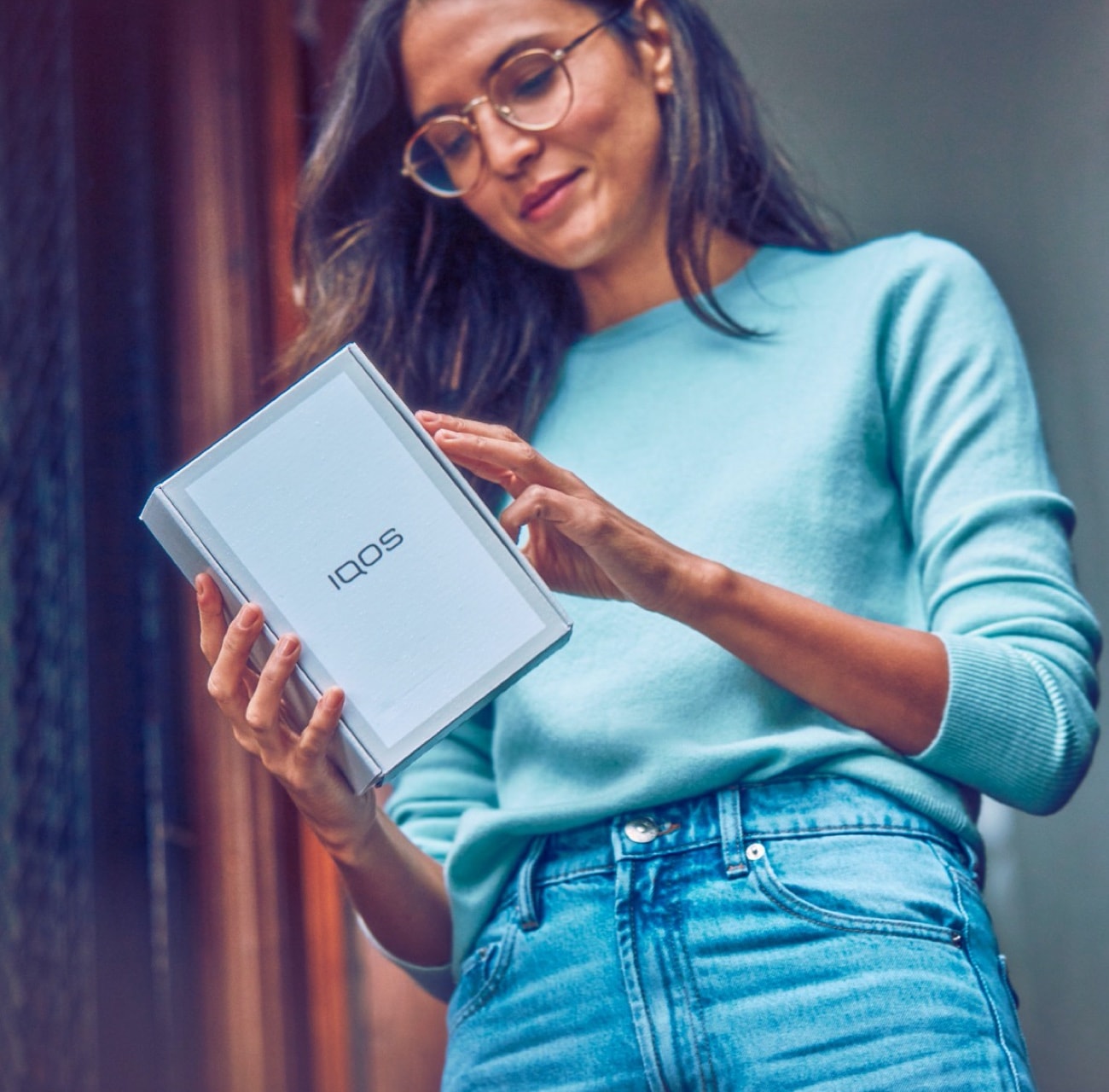 A woman holding an IQOS device box