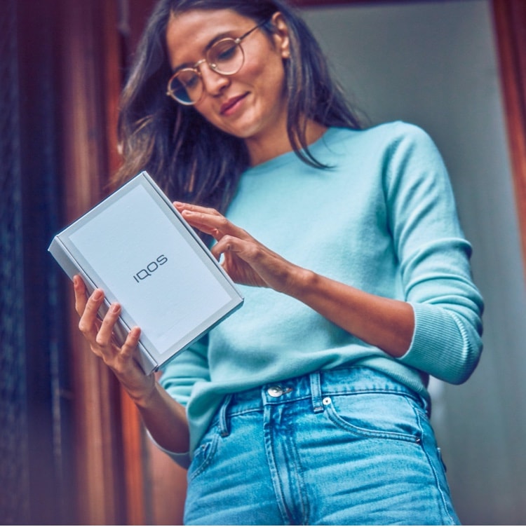 A woman holding an IQOS device box
