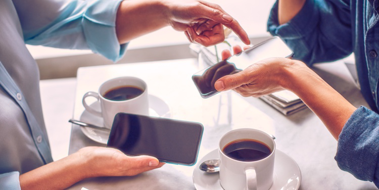 Two people with mobile phones having coffee.