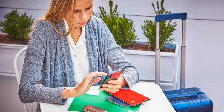 A woman using a mobile phone; her passport and IQOS device nearby. A woman using a mobile phone; her passport and IQOS device nearby.