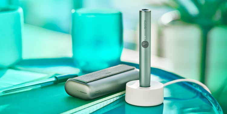 A Jade Green IQOS ILUMA PRIME Holder in a charging station.