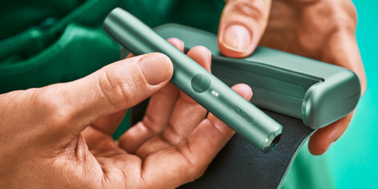 An IQOS ILUMA PRIME Holder in a person's hands, the lights visibile.