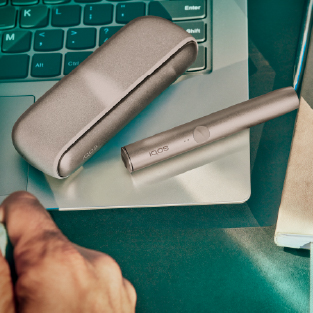 A gold IQOS ILUMA Holder and Pocket Charger on a laptop.