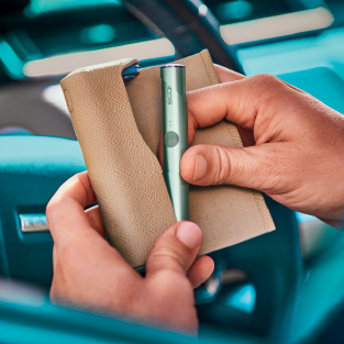A hand placing an IQOS ILUMA PRIME holder into a full wrap.