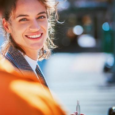 A smiling woman in a street scene.