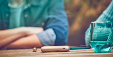 IQOS DUO on a table while two people are talking IQOS DUO on a table while two people are talking