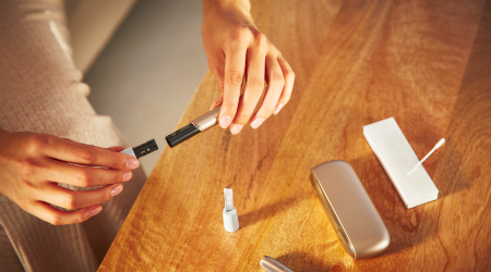Woman opening her IQOS holder with Cleaning sticks and other accessories on a table