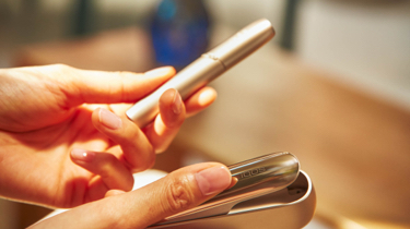 Woman with a golden IQOS holder and charger in her hand