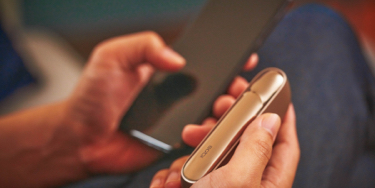 Man with a gold IQOS Duo and a mobile in his hands Man with a gold IQOS Duo and a mobile in his hands
