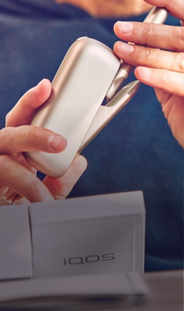 Close up of a person holding an IQOS device.